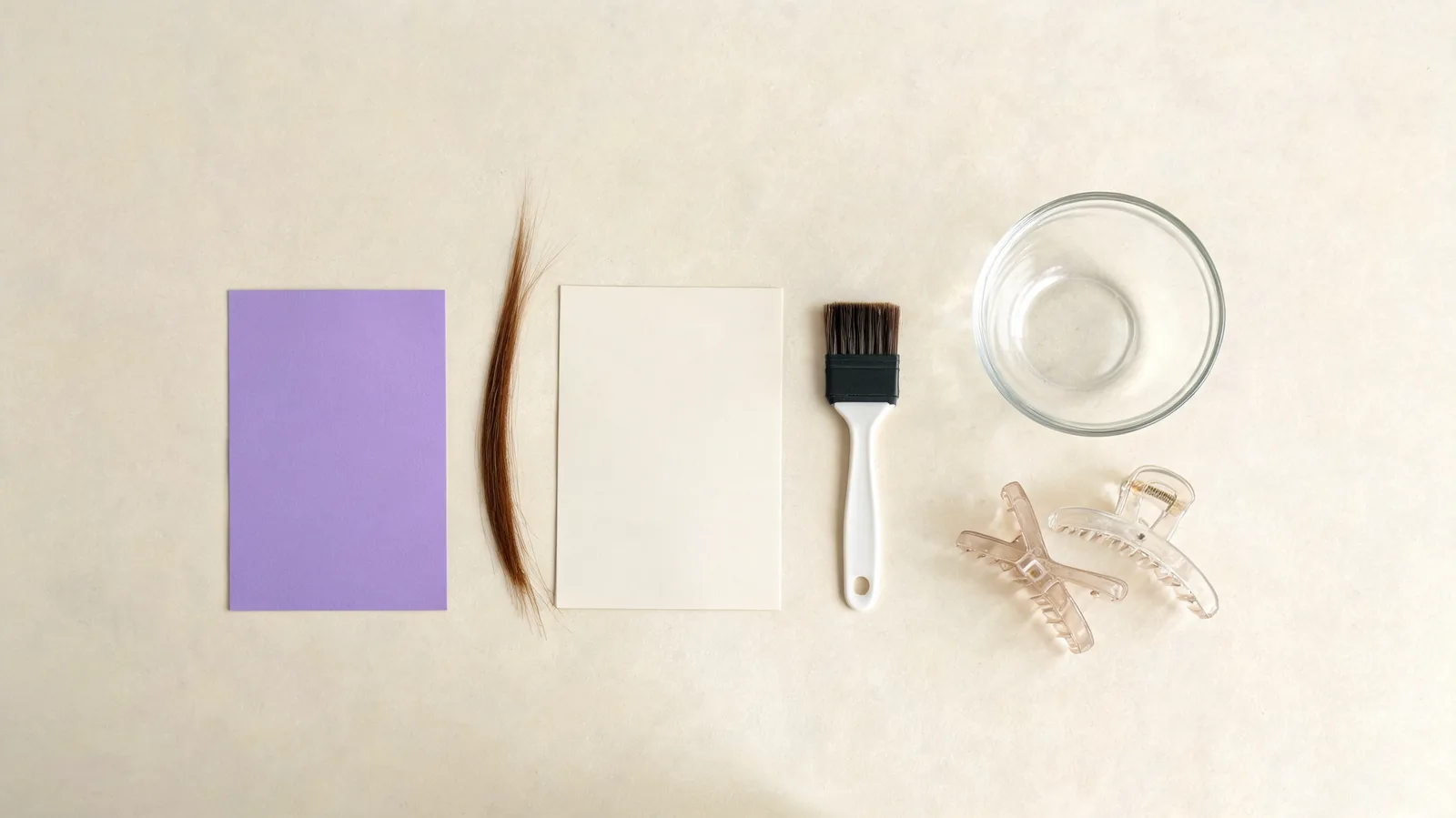 Editorial purple-hair consultation workspace with an unlabelled violet reference card, a neutral hair-history note card, a hair strand, and salon tools on a clean table